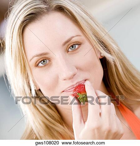 Stock Image - Portrait of a young woman holding a strawberry. Fotosearch