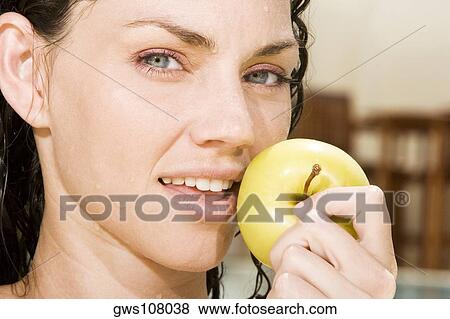 Stock Photo - Portrait of a young woman holding a green apple. Fotosearch