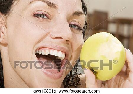 Stock Photography - Portrait of a young woman holding a green apple. Fotosearch