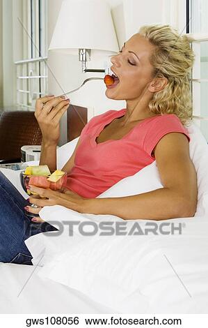Stock Photograph - Young woman eating a strawberry. Fotosearch