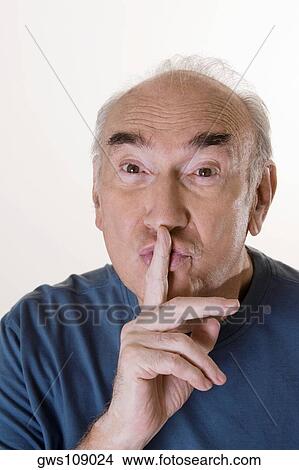 Picture - Close-up of a senior man with his finger on his lips. Fotosearch