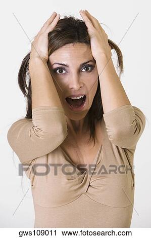 Stock Image - Close-up of a young woman with her hands on her head. Fotosearch