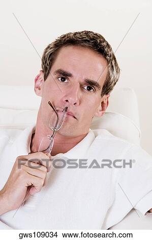 Portrait of a young man holding a pair of eyeglasses View Large Photo Image Picture - Portrait of a young man holding a pair of eyeglasses. Fotosearch