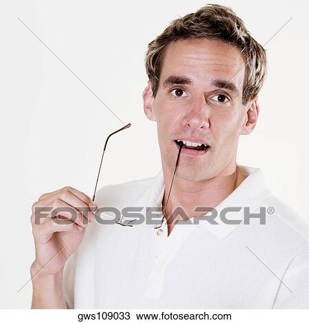 Portrait of a young man holding a pair of eyeglasses View Large Photo Image Stock Image - Portrait of a young man holding a pair of eyeglasses. Fotosearch