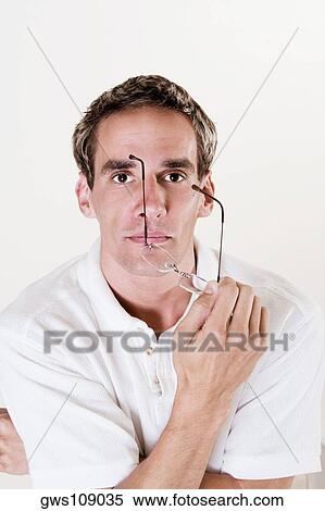 Portrait of a young man holding a pair of eyeglasses View Large Photo Image Stock Photography - Portrait of a young man holding a pair of eyeglasses. Fotosearch
