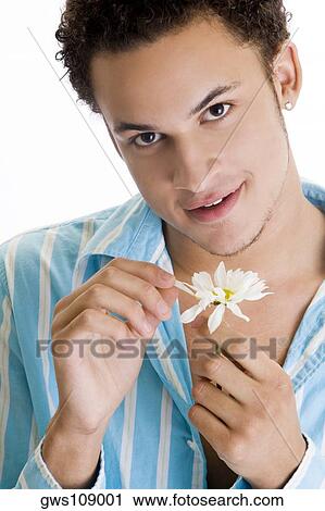 Portrait of a young man picking petals from a flower View Large Photo Image Stock Image - Portrait of a young man picking petals from a flower. Fotosearch