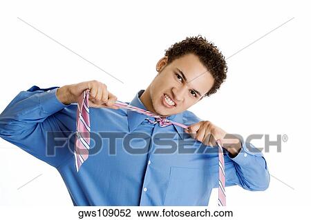 Portrait of a young man pulling his tie View Large Photo Image Stock Image - Portrait of a young man pulling his tie. Fotosearch