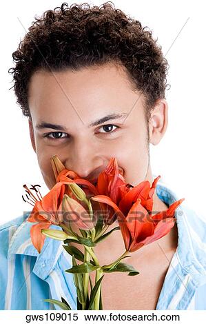 Stock Photography - Portrait of a young man sniffing flowers. Fotosearch