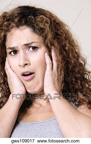 Stock Photo - Portrait of a young woman with her hands on her face. Fotosearch