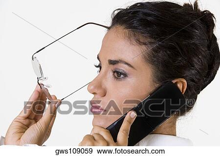 Stock Photo - Side profile of a young woman talking on a mobile phone. Fotosearch