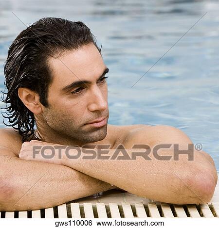Stock Photograph - Close-up of a mid adult man leaning at the edge of a swimming pool. Fotosearch