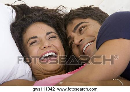 Stock Image - Close-up of a young couple lying on the bed. Fotosearch
