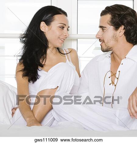 Close-up of a young couple sitting on the bed and looking at each other View Large Photo Image Stock Photo - Close-up of a young couple sitting on the bed and looking at each other. Fotosearch