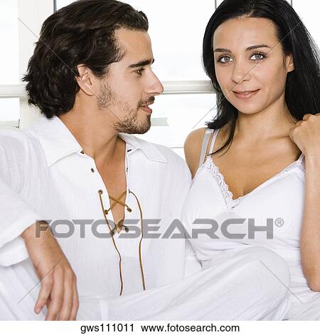 Close-up of a young couple sitting together on the bed View Large Photo Image Stock Image - Close-up of a young couple sitting together on the bed. Fotosearch