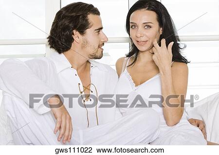 Stock Image - Close-up of a young couple sitting together on the bed. Fotosearch
