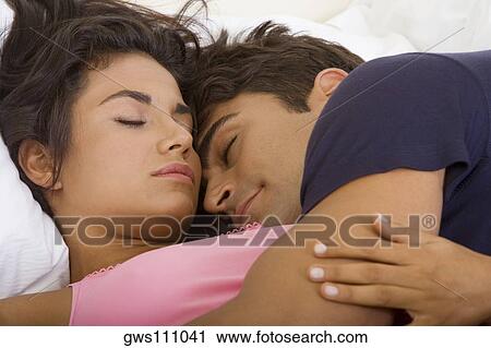 Stock Image - Close-up of a young couple sleeping on a bed. Fotosearch