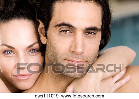 Stock Photo - Portrait of a young woman embracing a mid adult man from behind. Fotosearch
