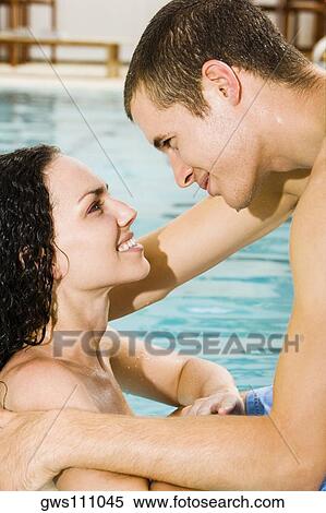 Stock Photography - Side profile of a young couple in a swimming pool. Fotosearch