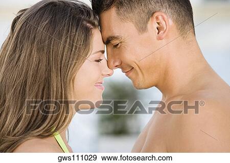 Stock Photo - Side profile of a young couple rubbing their noses. Fotosearch