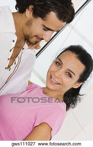 Stock Photo - Side profile of a young couple smiling. Fotosearch