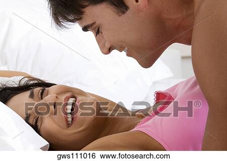Stock Photograph - Side profile of a young man lying on top of a young woman. Fotosearch