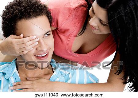 Stock Image - Young woman covering a young man's eye. Fotosearch