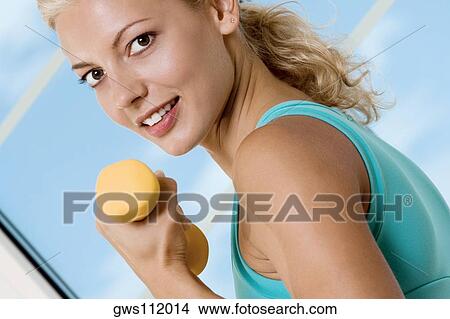 Close-up of a young woman exercising with dumbbells View Large Photo Image Picture - Close-up of a young woman exercising with dumbbells. Fotosearch