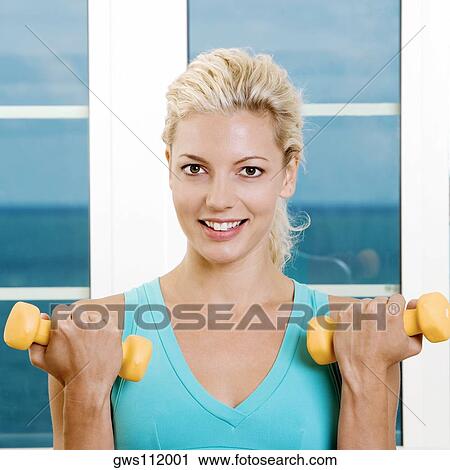 Close-up of a young woman holding dumbbells View Large Photo Image Stock Image - Close-up of a young woman holding dumbbells. Fotosearch