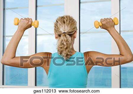 Close-up of a young woman holding dumbbells View Large Photo Image Stock Image - Close-up of a young woman holding dumbbells. Fotosearch
