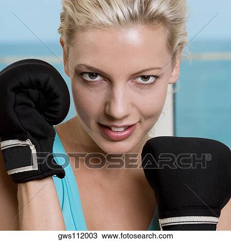 Stock Image - Close-up of a young woman wearing boxing gloves. Fotosearch