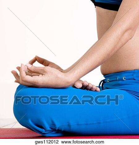 Stock Image - Mid section view of a young woman performing yoga. Fotosearch