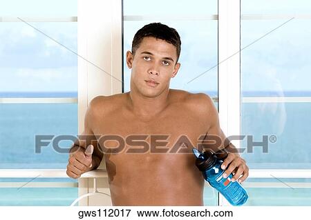 Portrait of a young man holding a bottle of water View Large Photo Image Stock Photo - Portrait of a young man holding a bottle of water. Fotosearch