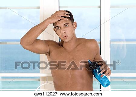 Portrait of a young man holding a bottle of water with hand on his head View Large Photo Image Stock Photo - Portrait of a young man holding a bottle of water with hand on his head. Fotosearch