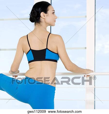 Rear view of a young woman performing stretching exercises View Large Photo Image Stock Photo - Rear view of a young woman performing stretching exercises. Fotosearch