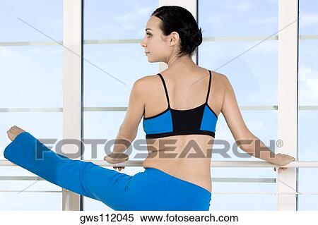 Rear view of a young woman performing stretching exercises View Large Photo Image Stock Photography - Rear view of a young woman performing stretching exercises. Fotosearch