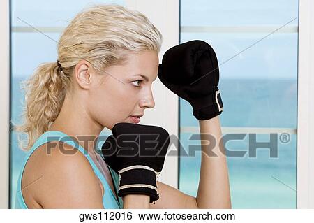 Side profile of a young woman wearing boxing gloves View Large Photo Image Stock Photograph - Side profile of a young woman wearing boxing gloves. Fotosearch