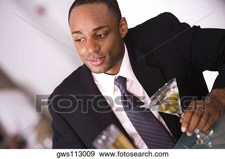 Close-up of a businessman holding a glass of martini View Large Photo Image Stock Photo - Close-up of a businessman holding a glass of martini. Fotosearch
