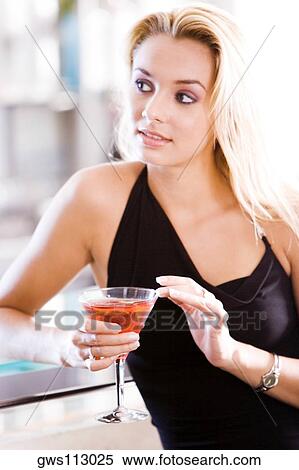 Close-up of a young woman holding a glass of martini View Large Photo Image Stock Photography - Close-up of a young woman holding a glass of martini. Fotosearch