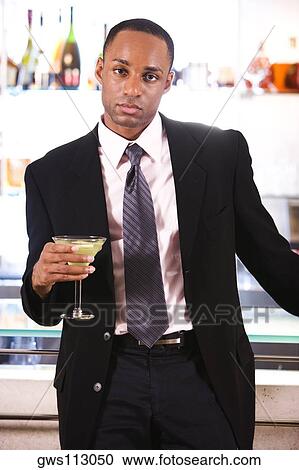 Portrait of a businessman leaning against a bar counter holding a martini glass View Large Photo Image Stock Image - Portrait of a businessman leaning against a bar counter holding a martini glass. Fotosearch
