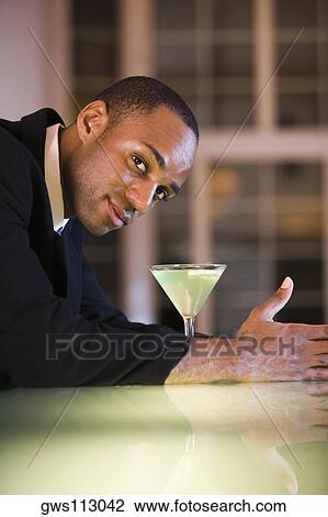 Portrait of a businessman with a martini in front of him View Large Photo Image Stock Image - Portrait of a businessman with a martini in front of him. Fotosearch