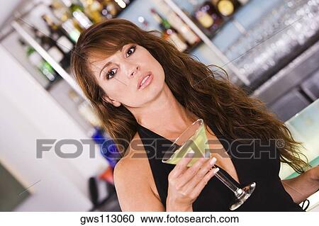 Portrait of a young woman holding a glass of martini View Large Photo Image Stock Image - Portrait of a young woman holding a glass of martini. Fotosearch