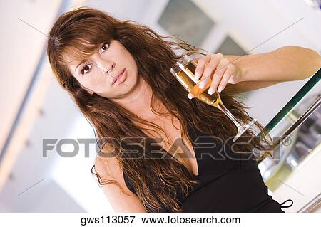 Portrait of a young woman holding a champagne flute View Large Photo Image Stock Photo - Portrait of a young woman holding a champagne flute. Fotosearch