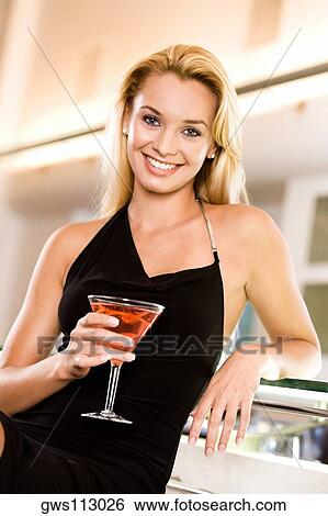 Portrait of a young woman holding a martini glass View Large Photo Image Stock Photograph - Portrait of a young woman holding a martini glass. Fotosearch