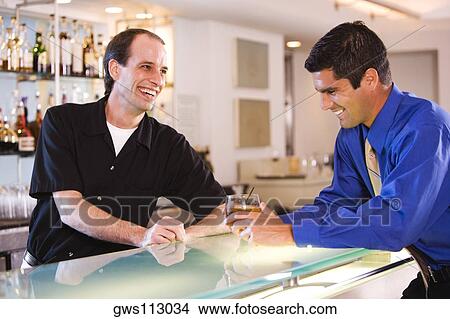 Side profile of a businessman and a bartender at a bar counter View Large Photo Image Picture - Side profile of a businessman and a bartender at a bar counter. Fotosearch