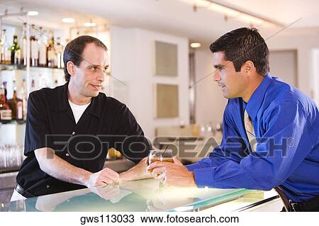 Side profile of a businessman and a bartender at a bar counter View Large Photo Image Stock Image - Side profile of a businessman and a bartender at a bar counter. Fotosearch
