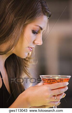 Side profile of a young woman holding a glass of martini View Large Photo Image Stock Image - Side profile of a young woman holding a glass of martini. Fotosearch