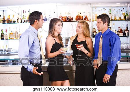 Two mid adult men and two young women standing in a bar View Large Photo Image Stock Image - Two mid adult men and two young women standing in a bar. Fotosearch