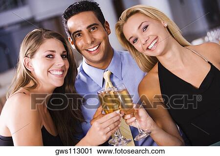 Two young women and a young man toasting with champagne flutes View Large Photo Image Stock Image - Two young women and a young man toasting with champagne flutes. Fotosearch