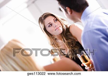 Young woman holding a champagne flute sitting with her friends at a restaurant View Large Photo Image Stock Image - Young woman holding a champagne flute sitting with her friends at a restaurant. Fotosearch