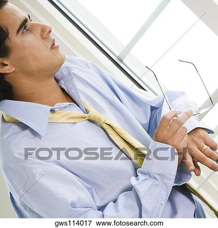 Stock Photo - Close-up of a businessman holding a pair of eyeglasses. Fotosearch